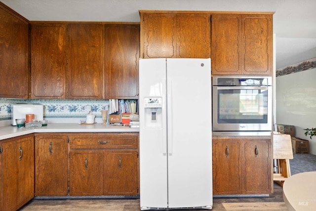 kitchen featuring light hardwood / wood-style flooring, oven, and white refrigerator with ice dispenser