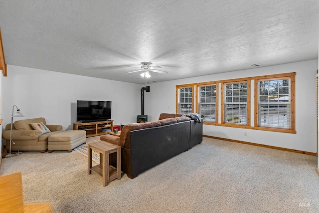 carpeted living room featuring ceiling fan, a wood stove, and a textured ceiling