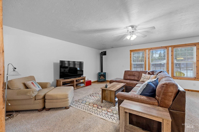 carpeted living room featuring a textured ceiling, a wood stove, and ceiling fan