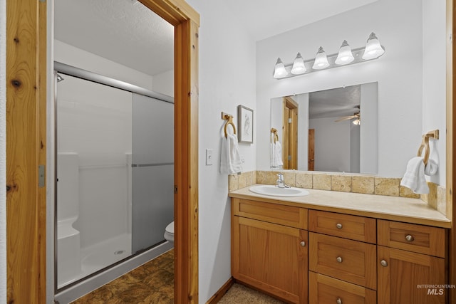 bathroom with vanity, ceiling fan, toilet, and walk in shower