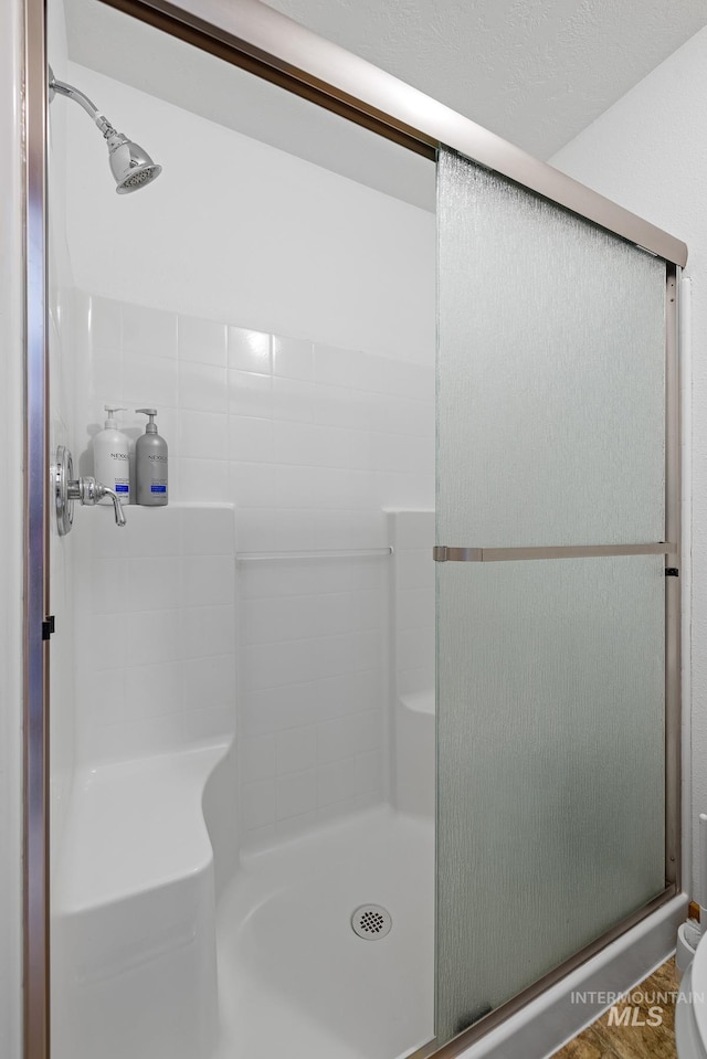 bathroom featuring wood-type flooring, a textured ceiling, and walk in shower