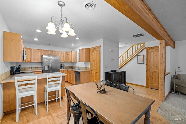 dining room with a textured ceiling, light wood-type flooring, sink, and an inviting chandelier