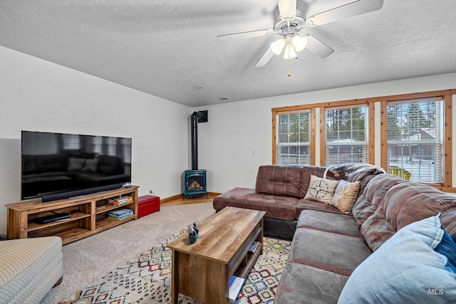 carpeted living room featuring ceiling fan, a wood stove, and a textured ceiling