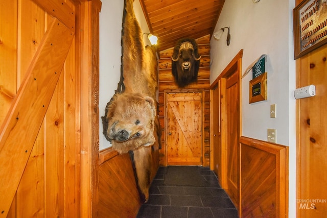 corridor with wooden ceiling, dark tile flooring, and vaulted ceiling