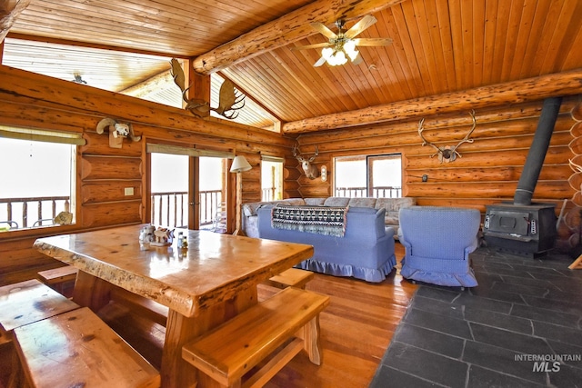 unfurnished living room with ceiling fan, rustic walls, and a wood stove