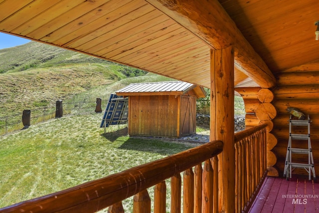 wooden terrace with a storage unit and a lawn