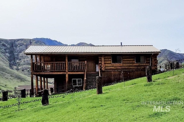 back of house featuring a mountain view and a lawn