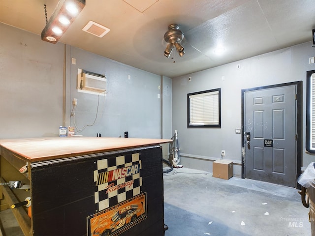 interior space featuring a wall mounted air conditioner, concrete floors, and ceiling fan