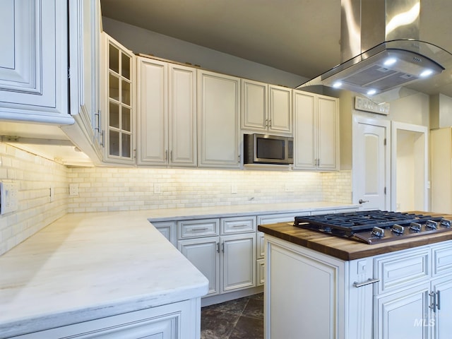 kitchen with island exhaust hood, decorative backsplash, stainless steel appliances, and white cabinetry