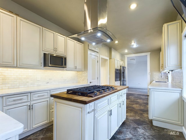 kitchen with wooden counters, decorative backsplash, a kitchen island, island range hood, and stainless steel appliances