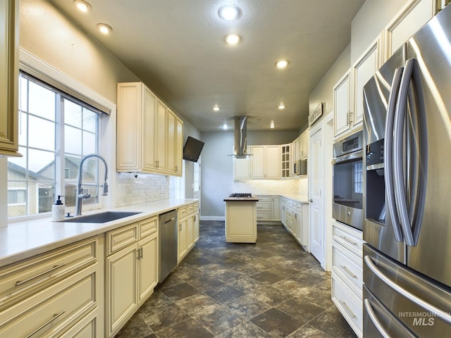 kitchen with cream cabinets, sink, tasteful backsplash, island range hood, and stainless steel appliances