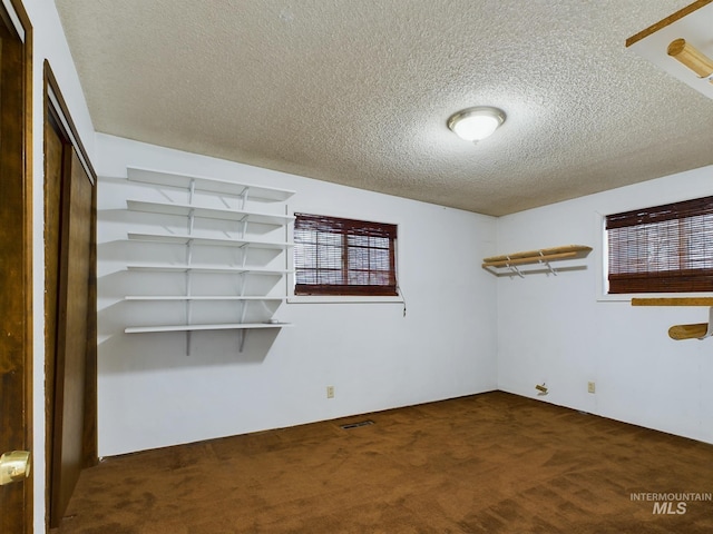 unfurnished bedroom with dark carpet and a textured ceiling