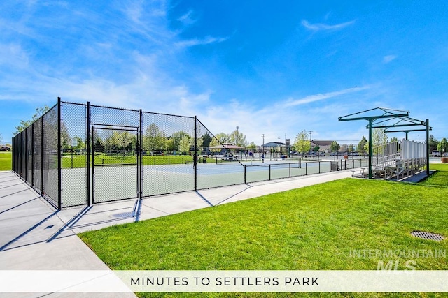 view of community featuring tennis court and a yard