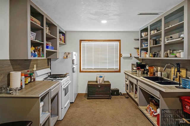 kitchen with open shelves, light carpet, white range with gas stovetop, and a sink