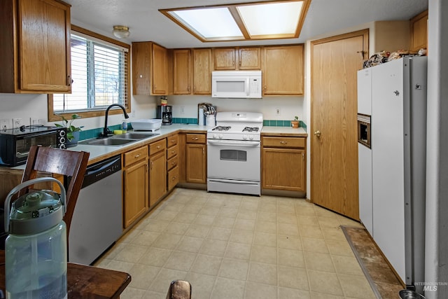 kitchen featuring a sink, white appliances, brown cabinetry, light countertops, and light floors