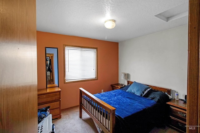 bedroom with carpet floors, a textured ceiling, and attic access