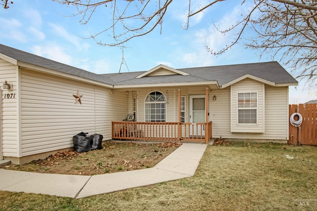single story home with covered porch, a shingled roof, a front lawn, and fence