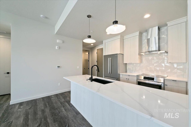 kitchen featuring pendant lighting, wall chimney exhaust hood, light stone counters, and sink