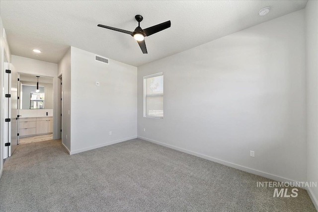 unfurnished bedroom with ensuite bath, ceiling fan, carpet, and a textured ceiling