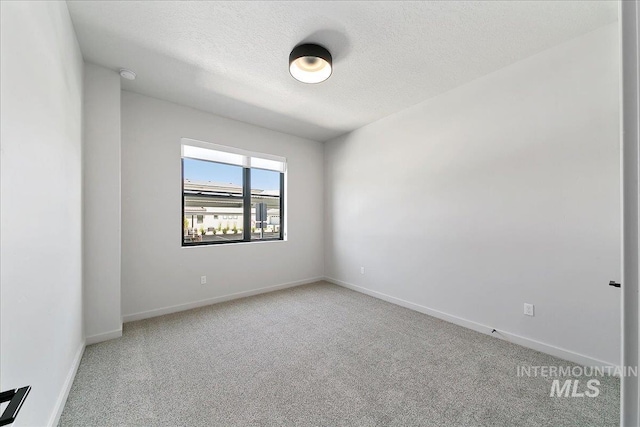 carpeted empty room featuring a textured ceiling