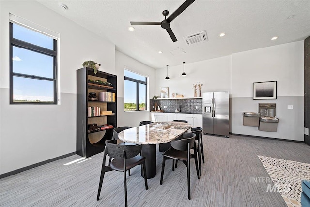 dining space with ceiling fan and light wood-type flooring