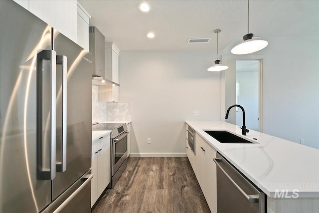 kitchen with white cabinetry, sink, wall chimney exhaust hood, stainless steel appliances, and pendant lighting