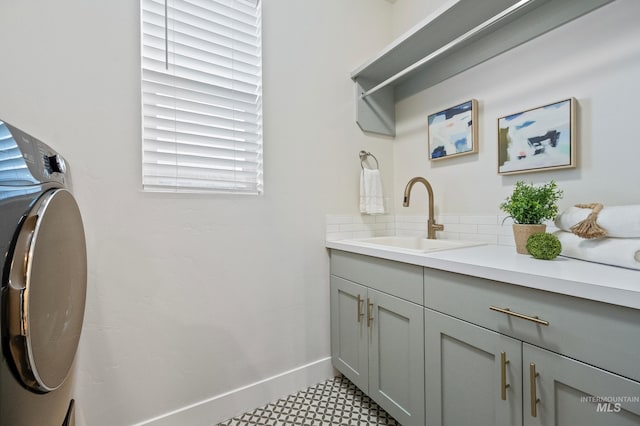 clothes washing area with cabinets, washer / clothes dryer, and sink