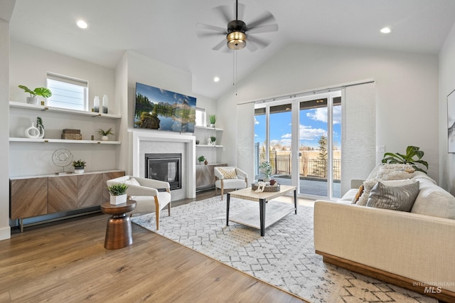 living room with hardwood / wood-style flooring, vaulted ceiling, ceiling fan, and built in shelves