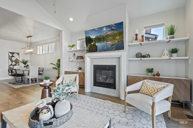 living room with an inviting chandelier, hardwood / wood-style floors, and vaulted ceiling