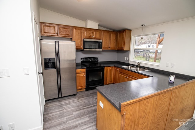 kitchen with kitchen peninsula, vaulted ceiling, sink, hardwood / wood-style floors, and stainless steel appliances