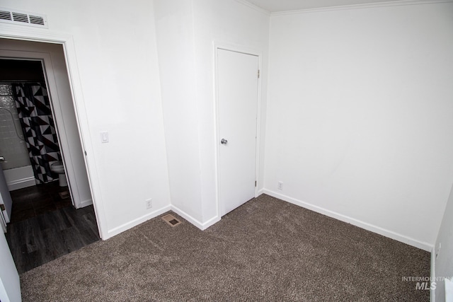 unfurnished bedroom featuring a closet, dark colored carpet, and ornamental molding