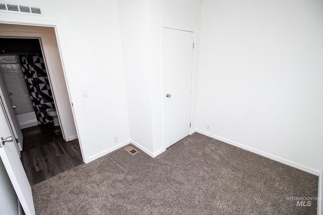 unfurnished bedroom featuring a closet and dark carpet