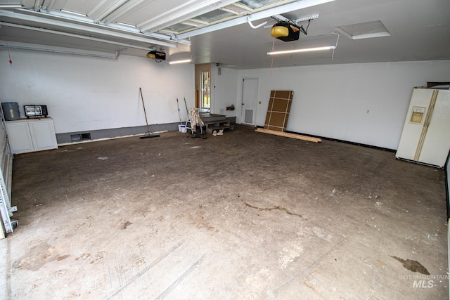 garage featuring white fridge with ice dispenser and a garage door opener