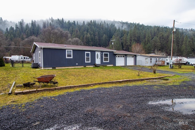 view of front of house with a garage, central AC, and a front yard