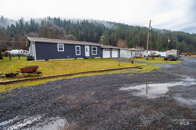 view of front of home featuring a garage, a front yard, and central air condition unit