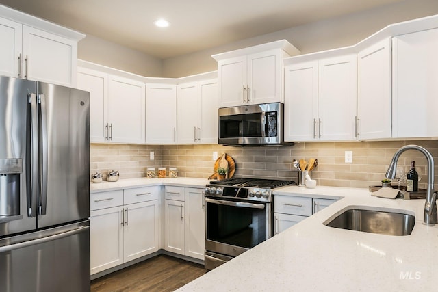 kitchen with sink, appliances with stainless steel finishes, light stone countertops, white cabinets, and decorative backsplash