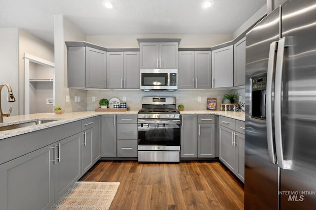 kitchen with appliances with stainless steel finishes, sink, gray cabinetry, and light stone counters