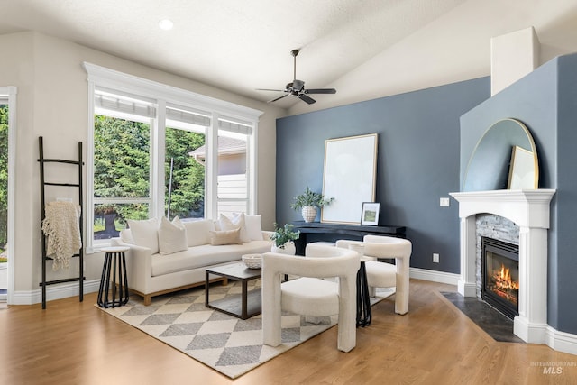 12258 Whitechapel Way, Nampa, ID 83686 - living room featuring ceiling fan, a stone fireplace, light wood finished floors, vaulted ceiling, and baseboards