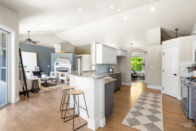 12258 Whitechapel Way, Nampa, ID 83686 - kitchen featuring ceiling fan, gas stove, a kitchen breakfast bar, light stone counters, and a peninsula