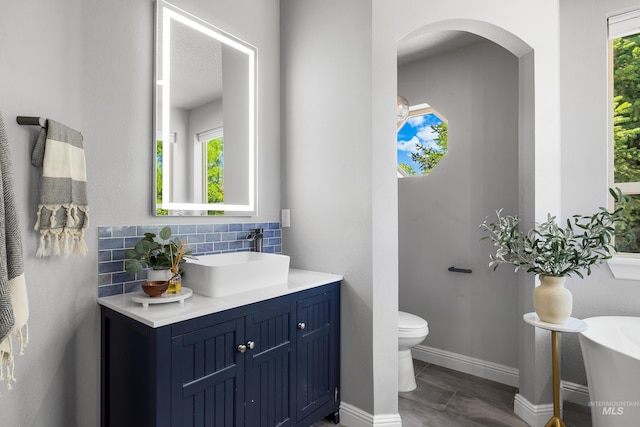 12258 Whitechapel Way, Nampa, ID 83686 - bathroom featuring toilet, vanity, tasteful backsplash, and baseboards