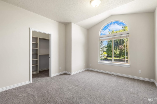 12258 Whitechapel Way, Nampa, ID 83686 - unfurnished bedroom with carpet floors, a walk in closet, vaulted ceiling, baseboards, and a textured ceiling