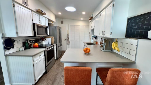 2927 N 32nd St, Boise, ID 83703 - kitchen featuring appliances with stainless steel finishes, light countertops, wood finished floors, a peninsula, and backsplash