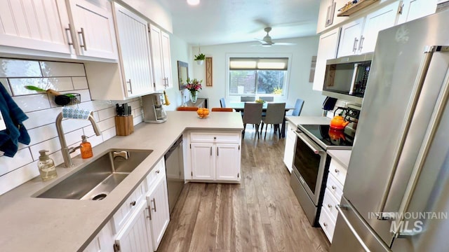 2927 N 32nd St, Boise, ID 83703 - kitchen featuring light wood-style flooring, appliances with stainless steel finishes, white cabinets, ceiling fan, and a peninsula