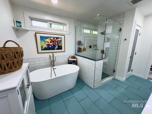 2927 N 32nd St, Boise, ID 83703 - bathroom featuring tile patterned floors, tile walls, a freestanding tub, visible vents, and a stall shower
