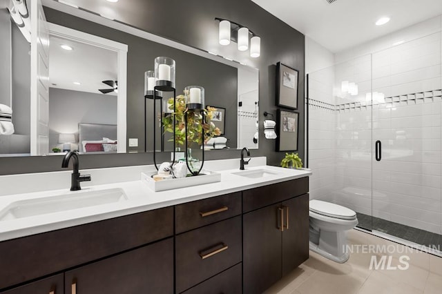 ensuite bathroom featuring tile patterned floors, a stall shower, double vanity, and a sink