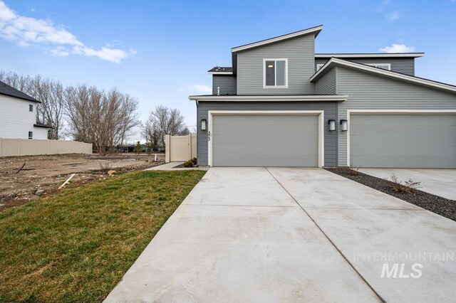 view of front of house featuring concrete driveway, a garage, and fence