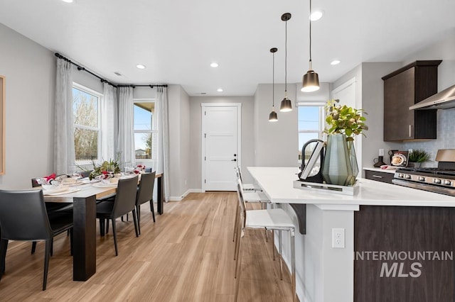 kitchen featuring tasteful backsplash, dark brown cabinetry, light wood-type flooring, light countertops, and gas stove