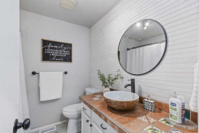 11457 S Cloverdale, Kuna, ID 83634 - bathroom featuring vanity, baseboards, toilet, wood walls, and visible vents