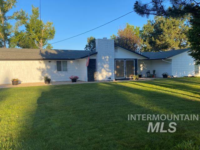 11457 S Cloverdale, Kuna, ID 83634 - rear view of property featuring a chimney and a lawn