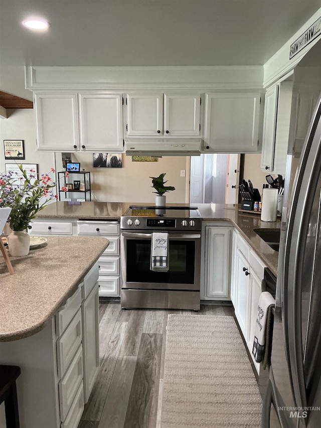 11457 S Cloverdale, Kuna, ID 83634 - kitchen featuring stainless steel appliances, under cabinet range hood, white cabinets, and wood finished floors